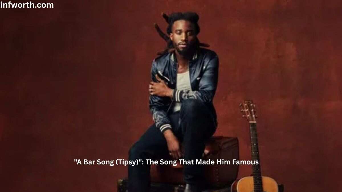 Shaboozey Net Worth – Shaboozey posing beside a guitar during a promotional photoshoot for his hit song "A Bar Song (Tipsy)."